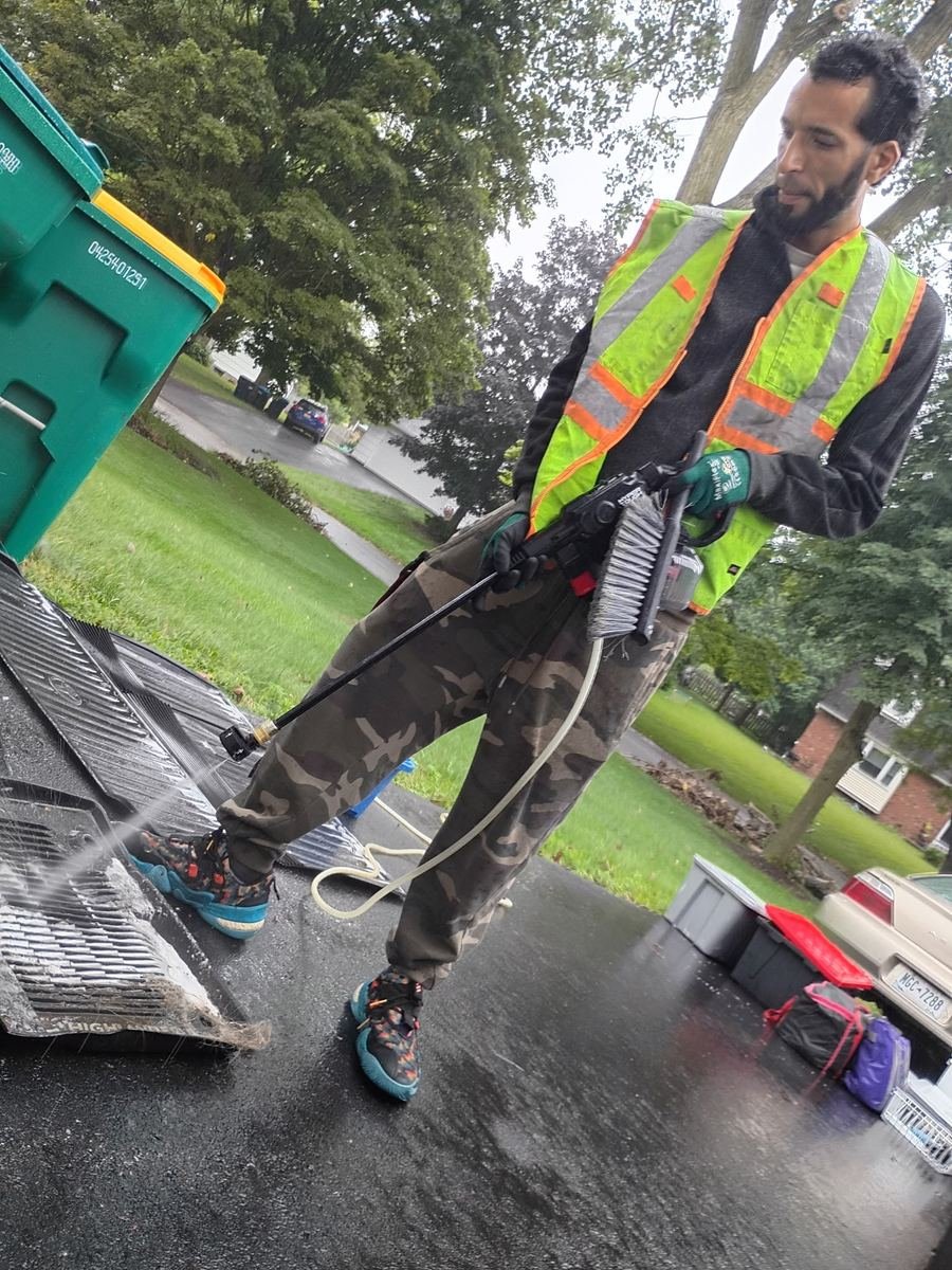 Slims technician pressure washing car floor mats during a detail