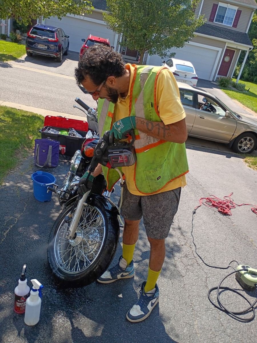 Slims technician pressure washing a motorcycle wheel during a mobile detail